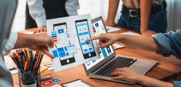 Panorama shot of frontend developer team brainstorming UI and UX designs for mobile app on paper wireframe interface User interface development team planning for userfriendly UI design Scrutinize