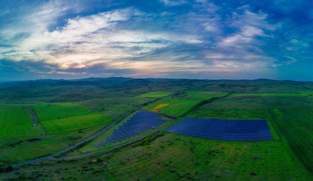 太陽の光からエネルギーを生成するソーラーパネルのパノラマは、太陽のある青い空の下の牧草地に設置されています