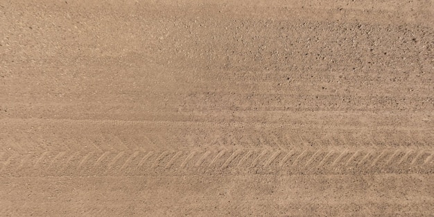 Panorama of surface from above of gravel road with car tire tracks