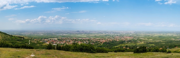 Panorama on town Plovdiv with houses and fields against backdrop of Rhodope Mountains covered with forest and cloudy sky