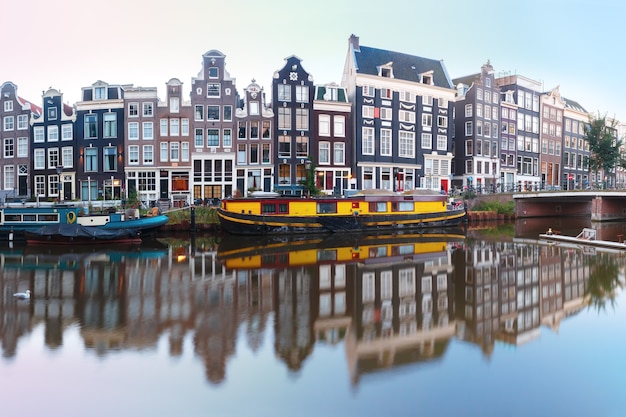 Panorama van Amsterdamse gracht Singel met typisch Nederlandse huizen, brug en woonboten tijdens ochtend blauw uur, Holland, Nederland.