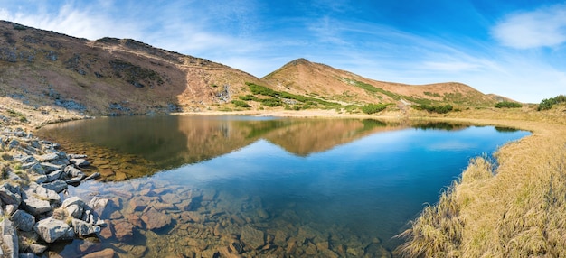 Panorama van bergenmeer met bezinning in blauw water, ochtendlicht en stralende zon