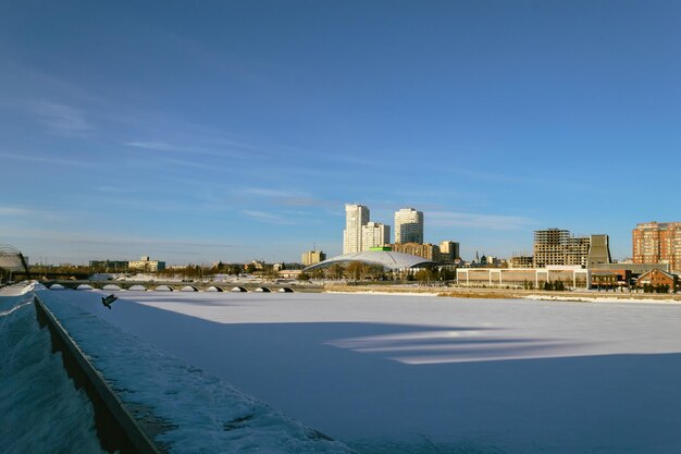 Panorama van een bevroren rivier en gebouwen verlicht door de zon op een winterdag