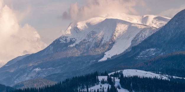 Panorama van hoge besneeuwde bergen die zich uitstrekken in de lucht met wolken