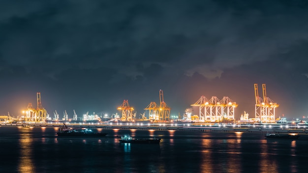 Foto panorama van kranen die verzendingcontainers laden in ladings verschepende haven bij nacht