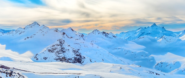 Panorama van sneeuw winter pieken in de bergen bereik. Landschap met avondrood en wolken