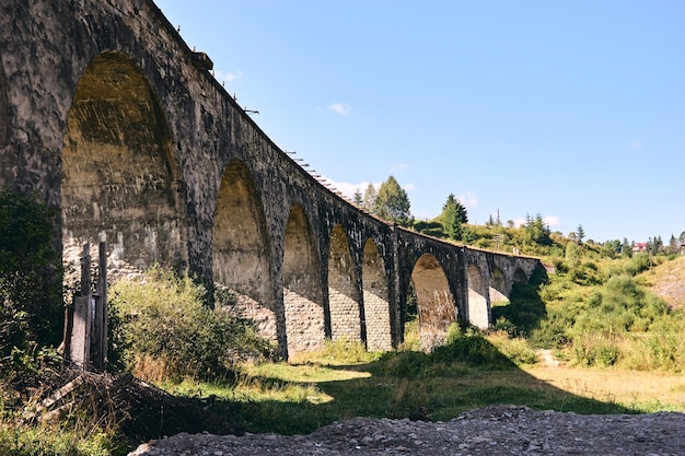 Foto vista panoramica del ponte antico. viadotto con vecchi binari ferroviari vicino alla collina verde della foresta di montagna. trova il concetto di viaggio.