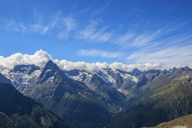 Фото Панорамный вид драматического голубого неба и гор в национальном парке домбай, кавказ, россия. летний пейзаж и солнечный день