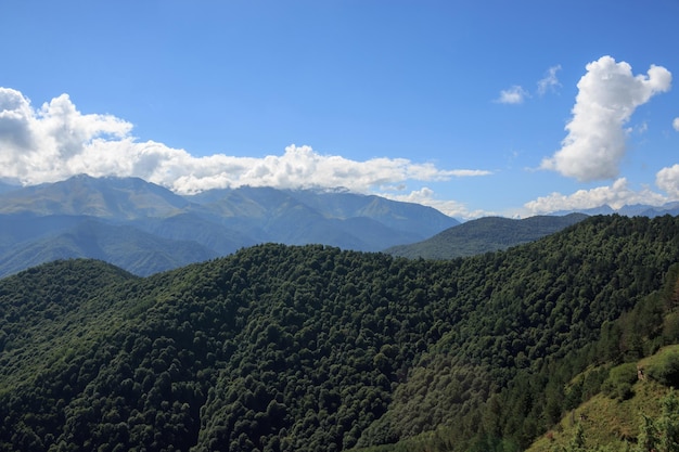 Фото Панорама гор в национальном парке домбай, кавказ, россия, европа. драматическое голубое небо и солнечный летний пейзаж