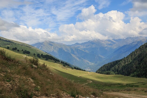 Фото Панорама гор в национальном парке домбай, кавказ, россия, европа. драматическое голубое небо и солнечный летний пейзаж