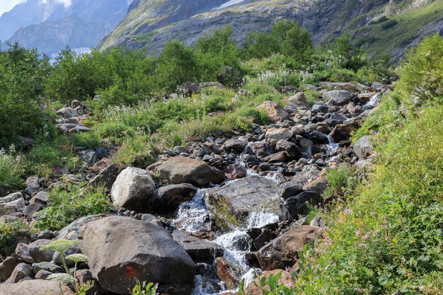 Panorama view of waterfall scene in mountains, national park of Dombay, Caucasus, Russia. Summer landscape, sunshine weather, dramatic blue sky and sunny day