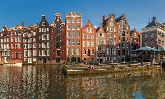 Panorama with beautiful typical dutch dancing houses at the amsterdam canal damrak in sunny day, holland, netherlands