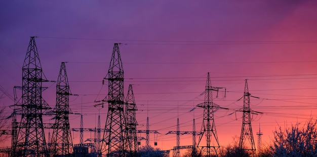 Panoramasilhouet van hoogspanningsleidingen tegen een kleurrijke hemel bij zonsopgang of zonsondergang