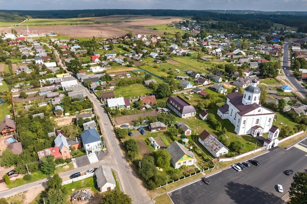 Фото Панорамный вид с воздуха на небольшой провинциальный городок или большую эко-деревню с деревянными домами, гравийными дорогами, садами и фруктовыми садами