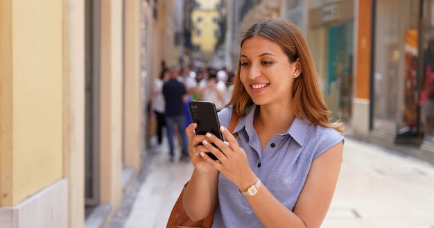 Panoramic banner of attractive busienss woman using mobile phone in the street with people on the background