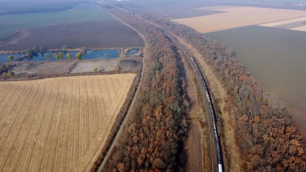 Panoramic moving freight train along railway tracks trees agricultural fields