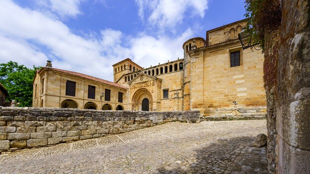 Panoramic of old stone Romanesque church with cobblestone pavement and blue sky