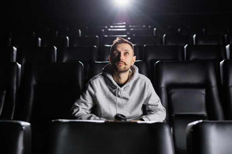 映画館で一人で映画を見ている焦点を絞ったスタイリッシュな男性のパノラマ写真
