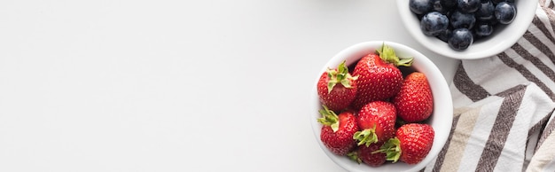 Panoramic shot of fresh and ripe strawberries and blueberries on bowls