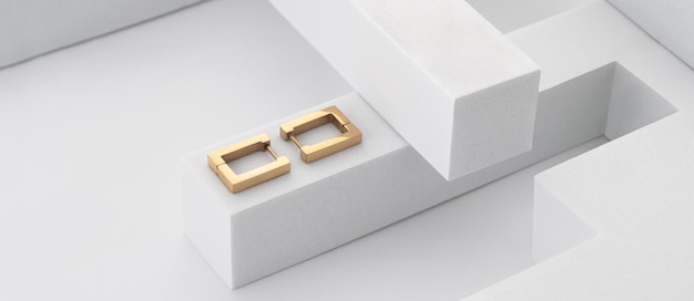 Panoramic shot of golden rectangular earrings pair on geometric white background