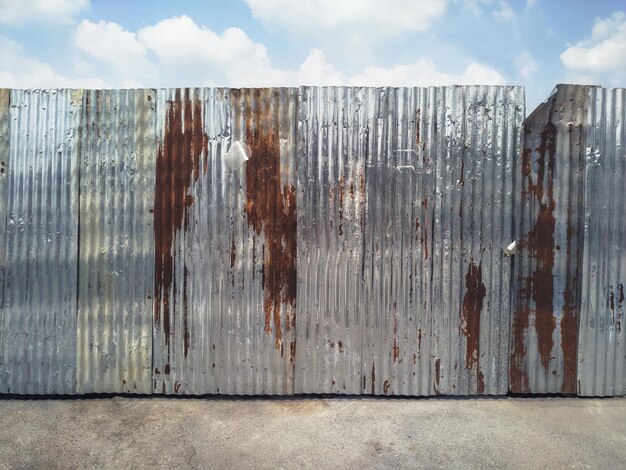 Panoramic shot of rusty metal fence against sky