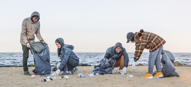 Panoramic shot of young students volunteers that cleaning up plastic on the beach