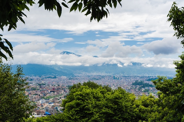 Panoramic top view of Katmandu city, capital of Nepal. Trees on foreground, stock photo.