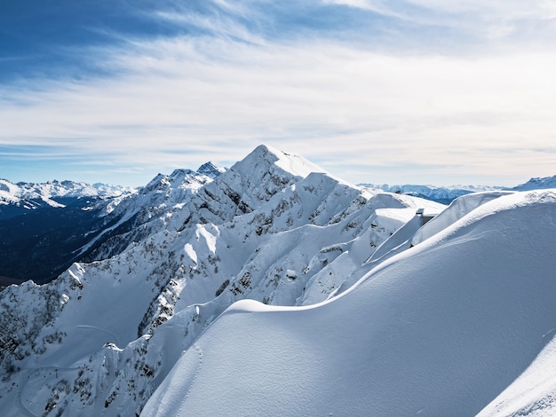 Панорамный вид на горный хребет Аибга с пиком Каменный столб на горнолыжном курорте Роза Хутор в солнечный зимний день. Сочи, Россия