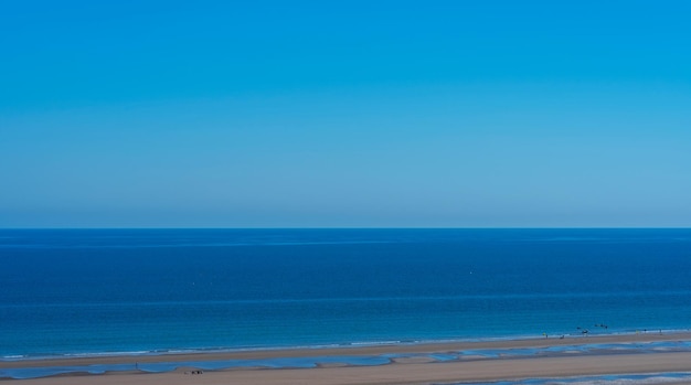 Vista panoramica della spiaggia dall'alto con sagome di persone sull'oceano e cielo sereno in estate