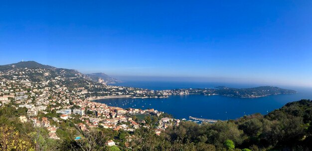 Panoramic view of city by sea against blue sky