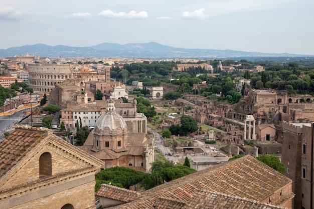 Panoramic view of city Rome with Roman forum and Colosseum from Vittorio Emanuele II Monument also known as the Vittoriano. Summer sunny day and dramatic blue sky