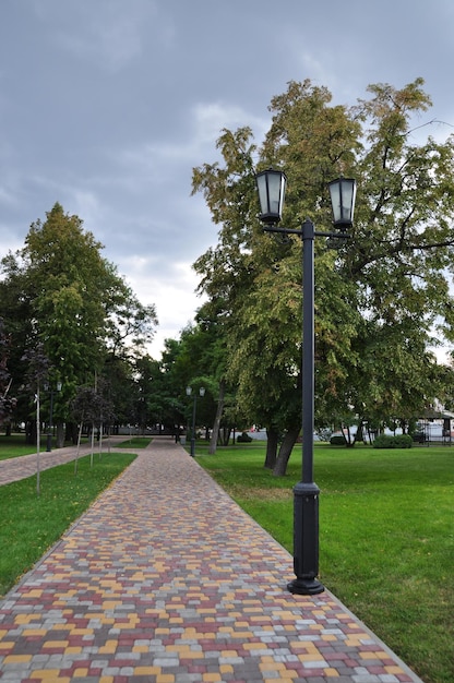 Panoramic view of the city square. Alley of the square made of multi-colored stones. Lantern with beautiful lamps.