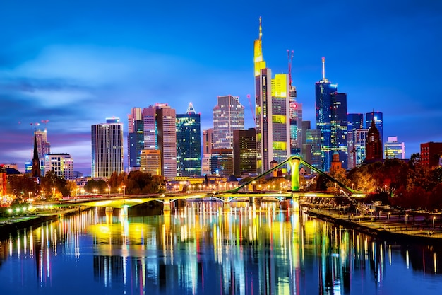 Panoramic view cityscape skyline of business district with skyscrapers and mirror reflections in the river Main during sunset blue hour, Frankfurt am Main. Hessen, Germany.