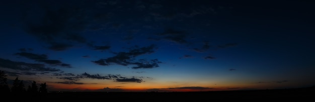 Panoramic view of the clouds in the sky after sunset. Evening twilight in summer.