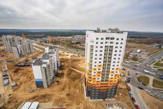 Panoramic view on construction of new quarter Tower unfinished multistorey high building from a bird's eye view with forest on background