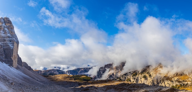 Panoramic view in Dolomites with clouds covering rocky mountains