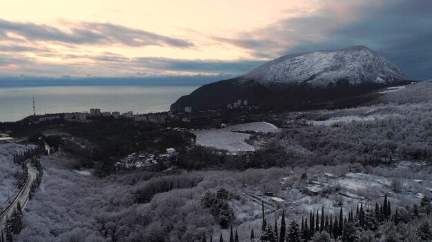 Photo panoramic view of the embankment of the city and snowcapped high mountain in sunset shot aerial for