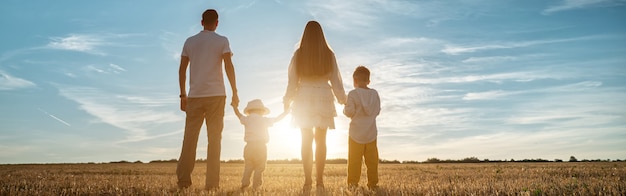 Photo panoramic view of family with children sons stands joining hands at sunset backside view