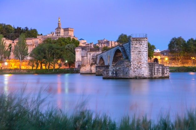 Photo panoramic view of famous medieval saint benezet bridge and palace of the popes during evening blue hour, avignon, southern france