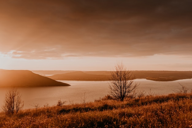 Panoramic view from the cliff to the big river lake sea in the distance silhouettes of the islands, fiery orange sunset sunset