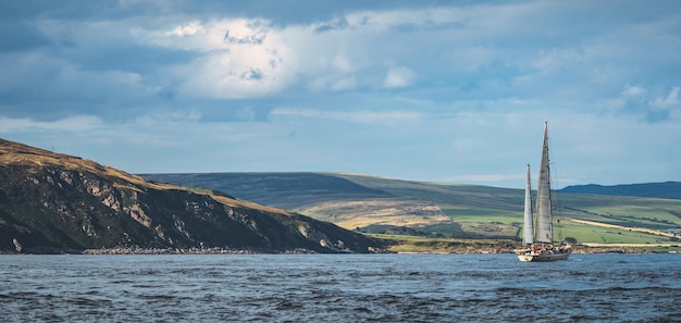 Vista panoramica del litorale irlandese lone yacht a vela tra le calme acque del mare irlanda del nord blue