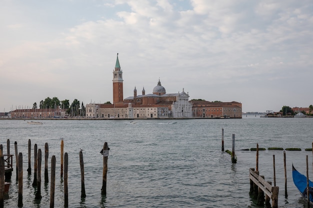 곤돌라와 멀리 산 조르지오 마조레 섬(San Giorgio Maggiore Island)이 있는 베니스(Venice) 시의 라구나 베네타(Laguna Veneta)의 탁 트인 전망. 여름 아침의 풍경과 극적인 푸른 하늘