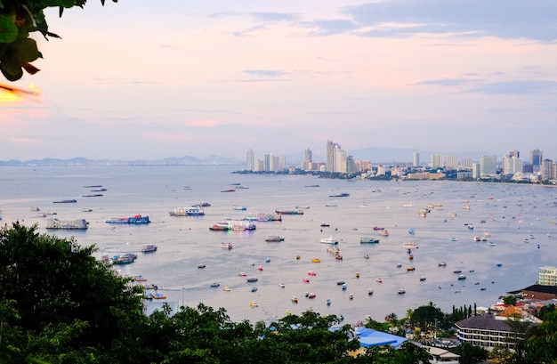 写真 日没のパタヤ市と夕暮れのタイの海でボートとヨットで街と湾のパノラマビュー