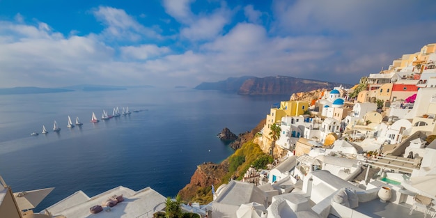 写真 サントリーニ島の名所のパノラマ ビュー 朝の有名なイアの町 海に浮かぶセーリング ヨットの列 良い休暇 白い家と紺碧の海