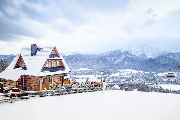 Foto vista panoramica della vecchia casa colonica tradizionale che si siede sulla cima di una collina nelle nuvole di paesaggio scenico del paese delle meraviglie di inverno
