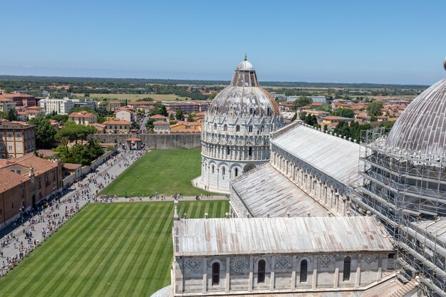 Panoramic view of Piazza del Miracoli with Pisa Baptistery of St. John and Pisa Cathedral from Tower of Pisa. People walk and rest on square