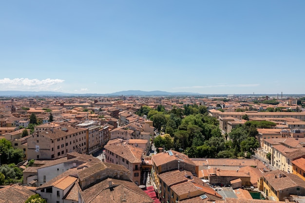 Panoramic view of Pisa city with historic buildings and far away mountains from Tower of Pisa. Summer day and sunny blue sky