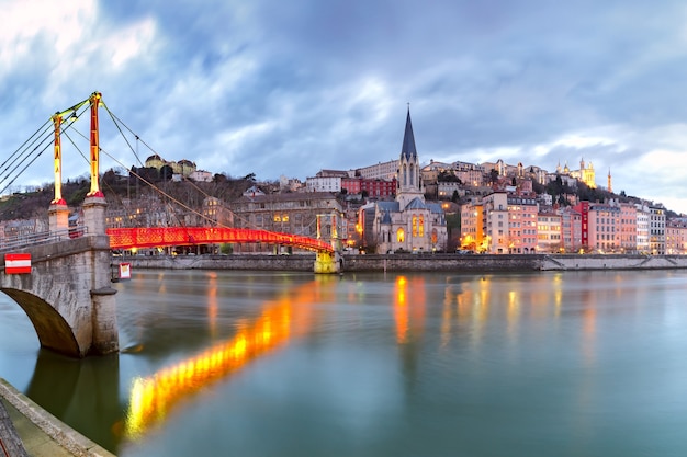 Panoramic view of Saint Georges church and footbridge across Saone river, Old town with Fourviere cathedral during evening blue hour in Lyon, France