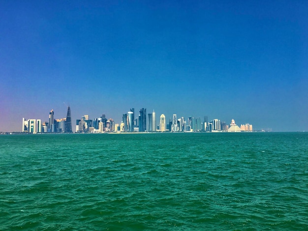 Panoramic view of sea and buildings against clear blue sky