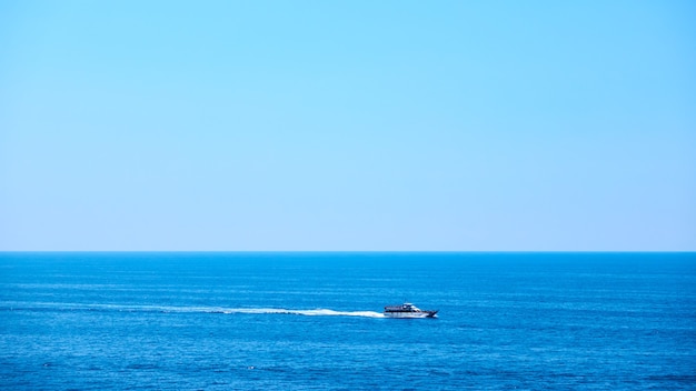 Panoramic view of the sea with small ship and clear blue sky